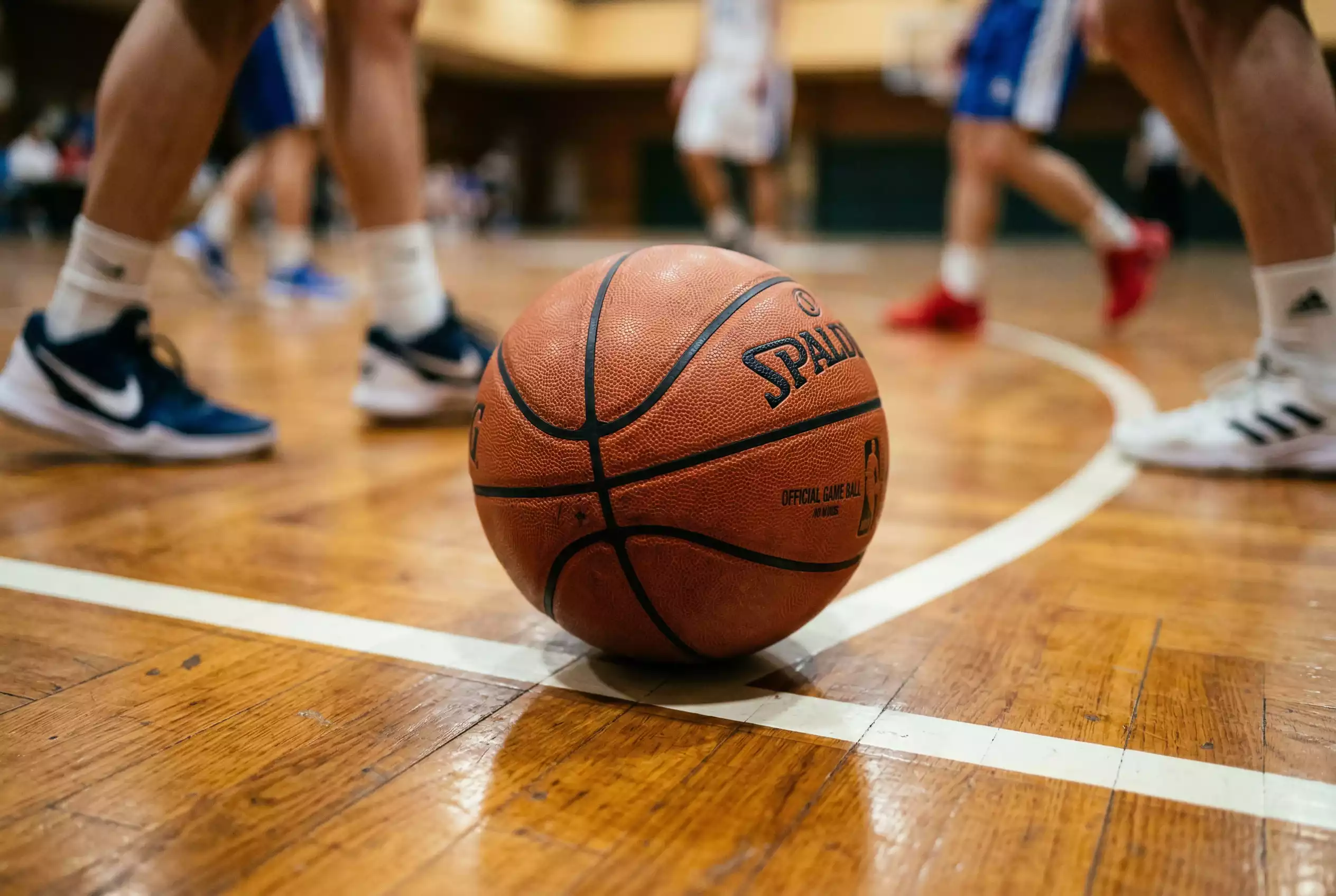 Basketball Wettarten – Nahaufnahme eines Basketballs auf dem Spielfeld mit Spielern im Hintergrund
